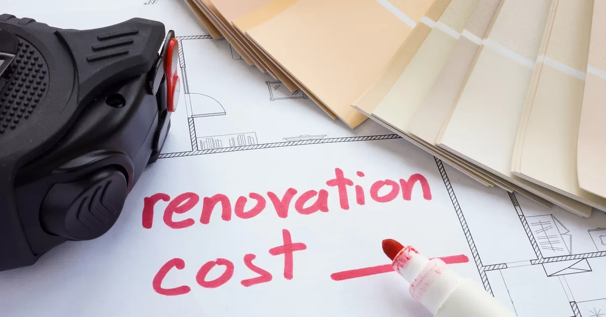 A red marker rests beside the words "renovation costs" on a blueprint with a color swatch and measuring tape nearby.