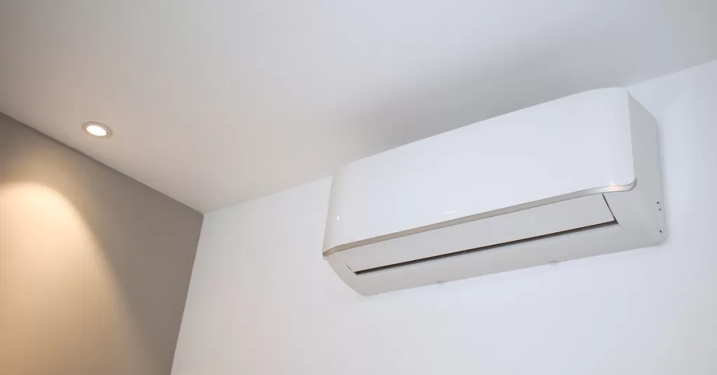 A mini split AC unit is installed at the top of a wall near the ceiling. There is a recessed light on the ceiling nearby.