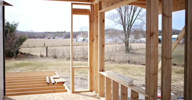 The back of a home has an additional dwelling unit being constructed. The subfloor and framing are visible.