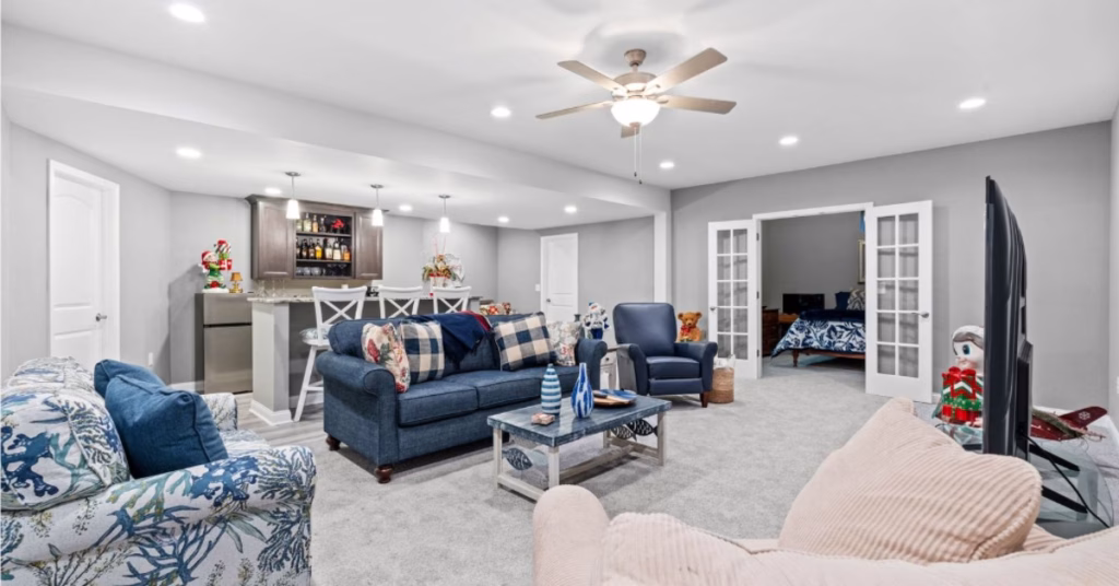 A finished basement lounge features a seating area, a wet bar, a bedroom entrance, and bright recessed lights.